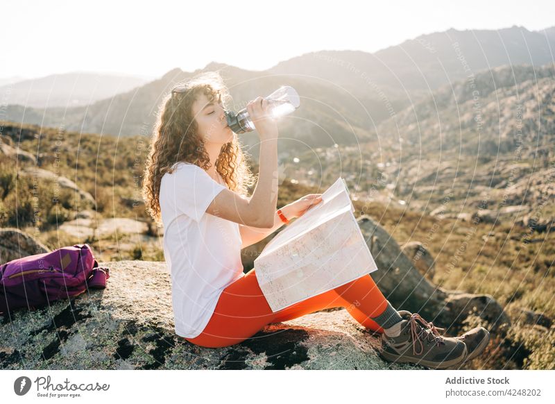 Junge Frau trinkt Wasser und liest Karte beim Wandern im Hochland trinken Berge u. Gebirge Wanderer Trekking Landkarte Durst Reisender müde Abenteuer Natur