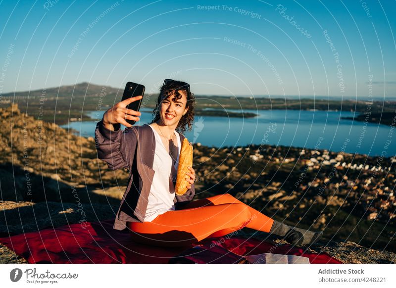 Reisende Frau macht Picknick und fotografiert mit Smartphone auf felsigem Berg essen Belegtes Brot Berge u. Gebirge Selfie Wanderer MEER Glück reisen