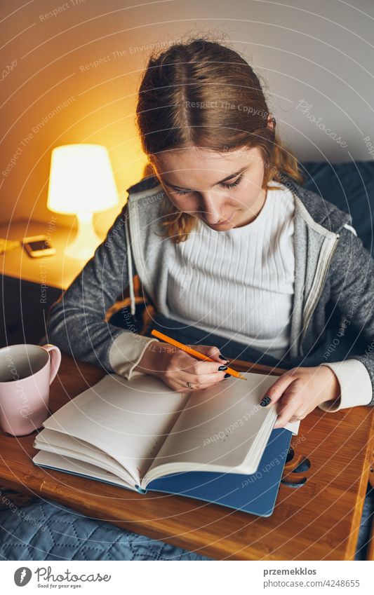Schüler lernen zu Hause. Junge Frau macht Notizen, Lesen und Lernen von Notizblock. Mädchen schreiben Journal sitzen im Bett Bildung im Innenbereich arbeiten