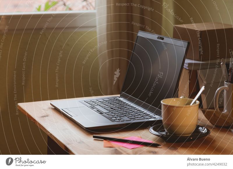 Das Home-Office, ein Beispiel für einen Raum für Telearbeit von zu Hause aus, wo man einen Laptop und eine Tasse Kaffee oder heißen Tee sieht, früh am Morgen, in Madrid, Spanien. Work-Life-Balance.