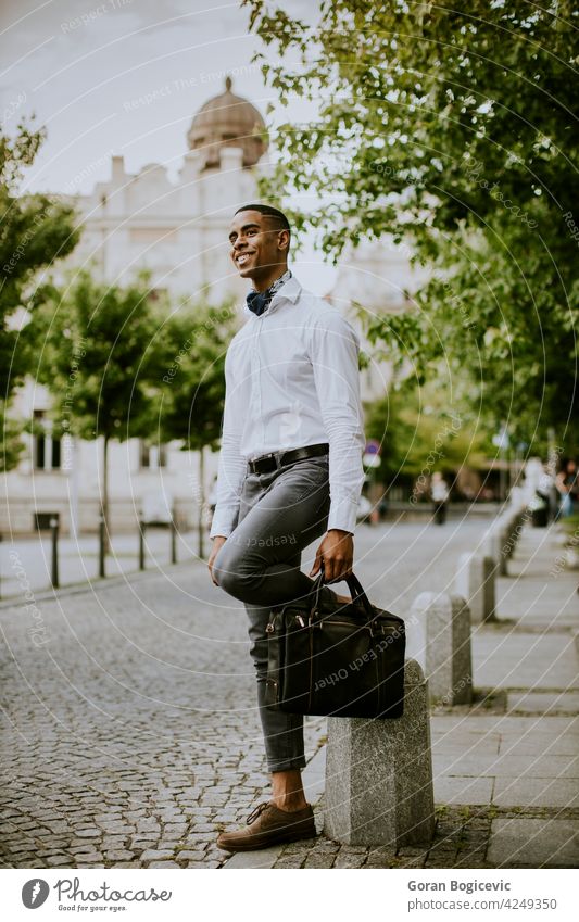 Junger afroamerikanischer Geschäftsmann wartet auf der Straße auf ein Taxi Gebäude Großstadt jung Menschen reisen Reisender modern Station Koffer Manager urban