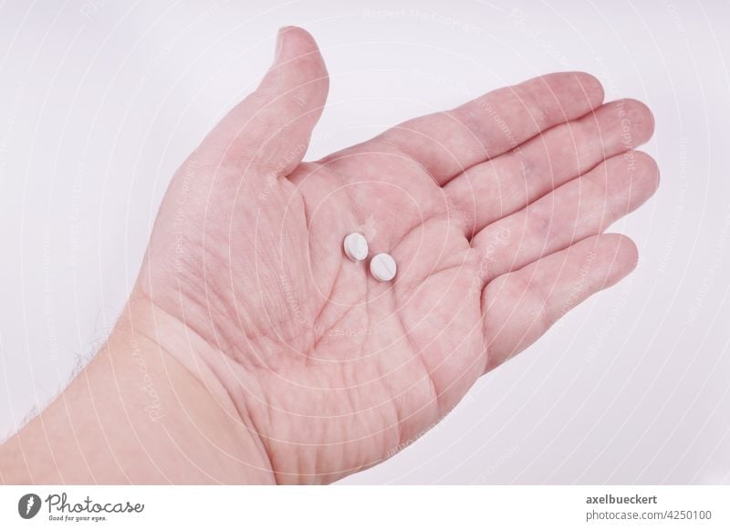 Tabletteneinnahme - Hand mit zwei Tabletten Medikamente Pillen Gesundheit Antihistaminikum Allergie Medizin Pharma Hilfsbereitschaft Schmerz Antibiotikum