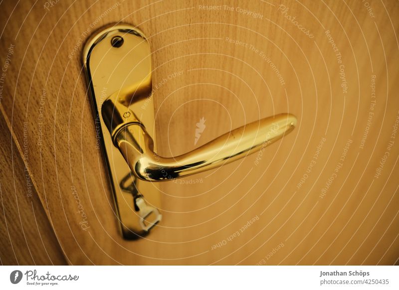 goldene Türklinke mit Schlüssel an Holztür in der Wohnung verschlossen Nahaufnahme Eingangstür Griff türklinke Türgriff geschlossen Menschenleer Schloss