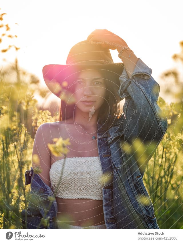 Frau mit Hut steht auf grünem Feld freudig Stil Blüte Sommer Natur sorgenfrei sonnig Raps feminin Blütezeit Gelassenheit emotional attraktiv schön Angebot