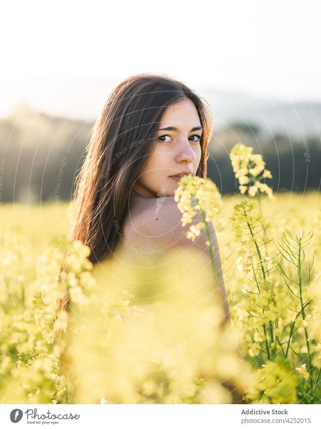 Gelassene Frau auf blühendem Feld stehend gelb Blume sensibel Blüte filigran feminin nackte Schultern Natur Blütezeit Gelassenheit friedlich attraktiv schön