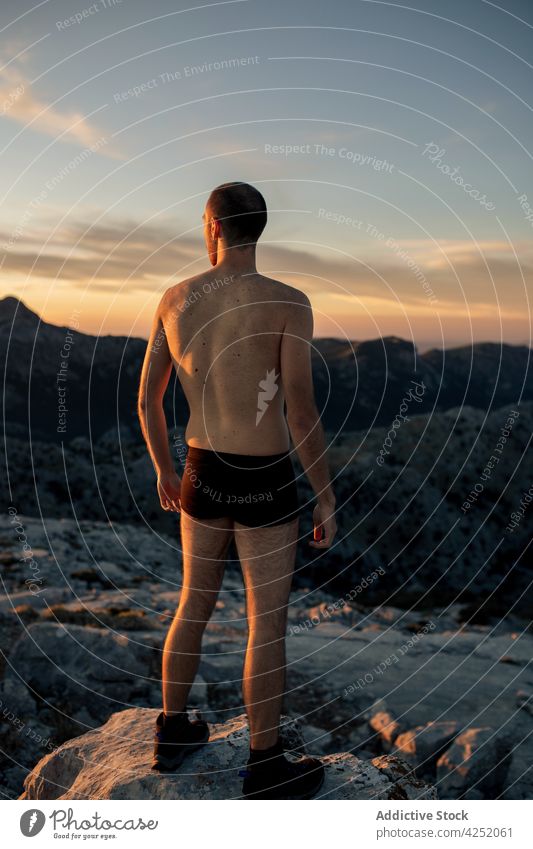 Unbekannter Mann in Badehose auf rauem Berggipfel stehend Berge u. Gebirge Wanderer bewundern Hochland Kofferraum Unterhose Ambitus Sonnenuntergang spektakulär