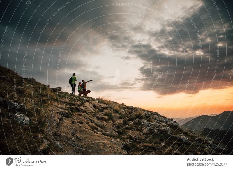 Reisende mit Hund am felsigen Berghang bei Sonnenuntergang Wanderer Menschengruppe beobachten Gipfel Berge u. Gebirge Reisender Zusammensein Freund erkunden