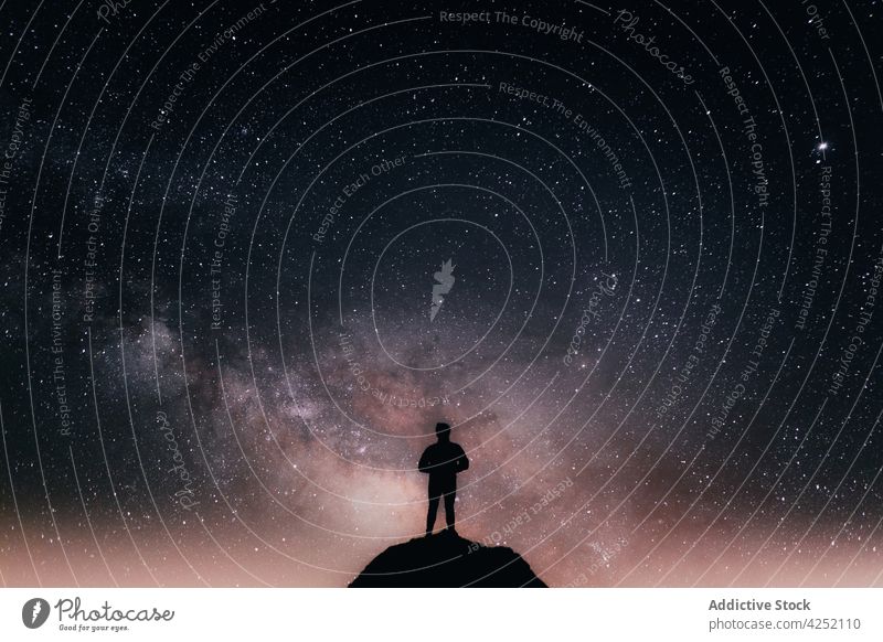 Reisender steht auf einem Felsen vor dem Sternenhimmel Mann Silhouette Nacht Klippe Astronomie Galaxie dunkel leuchten Milchstrasse männlich Natur sternenklar