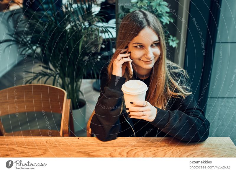Junge Frau am Telefon im Café, mit einem angenehmen Telefongespräch, Beantwortung von Anrufen, Chatten per Handy mit Freund, während in einem Café sitzen und Kaffee trinken. Mädchen entspannt im Café