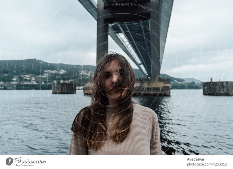 Porträt unter einer Brücke von einer Frau, die sein Haar bewegt, Zeitstopp, psychische Gesundheit Konzept mit Kopie Raum, moderne Meer, entspannen Person