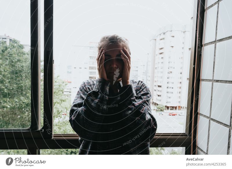 Besorgte Frau, die aus dem Fenster ihrer Wohnung schaut, Konzept der psychischen Gesundheit in der Stadt, Depression mit Kopierraum Angst Frustration