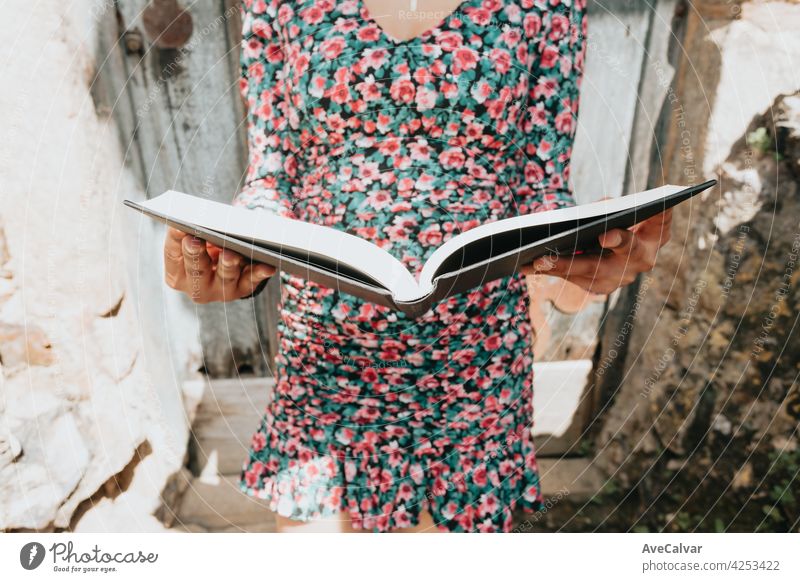 Nahaufnahme einer Frau in einem Kleid, die nach einem Buch greift, während sie es liest, mit Kopierraum Bildung Person Bibliothek Literatur offen Page lesen