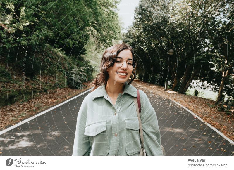Junge marokkanische Frau lächelnd zur Kamera in herbstlichen und entsättigten Farben mit Kopie Raum und moderne Kleidung lockig Hipster Teenager Lächeln
