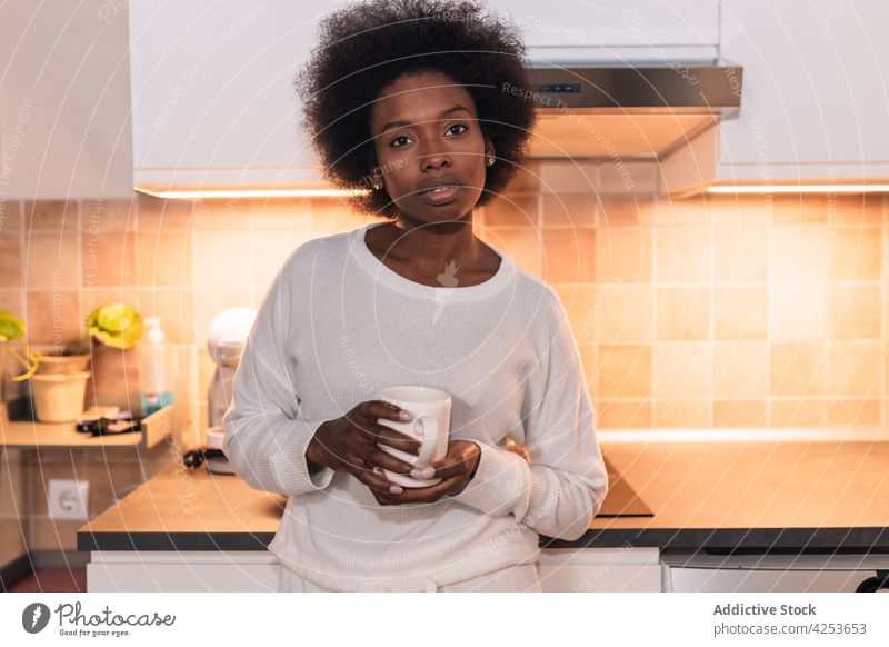 Ruhige junge afroamerikanische Frau trinkt Kaffee in der Küche trinken ernst Windstille Getränk Frühstück Koffein Erfrischung heimwärts wach Afroamerikaner
