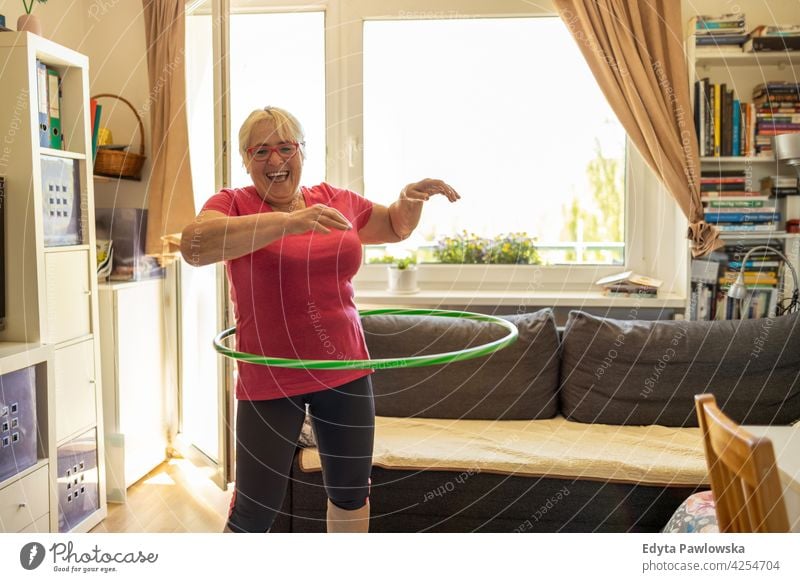 Ältere Frau Hula Hooping zu Hause Brille Falte natürlich echte Menschen lässig Tag Lifestyle Großmutter Rentnerin gealtert Freizeit Ruhestand Lebensalter