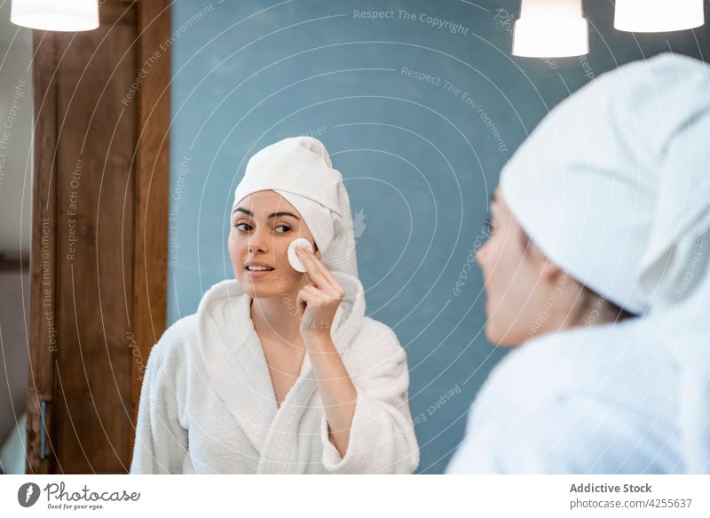 Junge Frau reinigt Gesicht mit Tonic Hautpflege reinigen Wischen Sauberkeit Unterlage täglich Morgen Leckerbissen Pflege Baumwolle Spiegel nasses Haar Handtuch