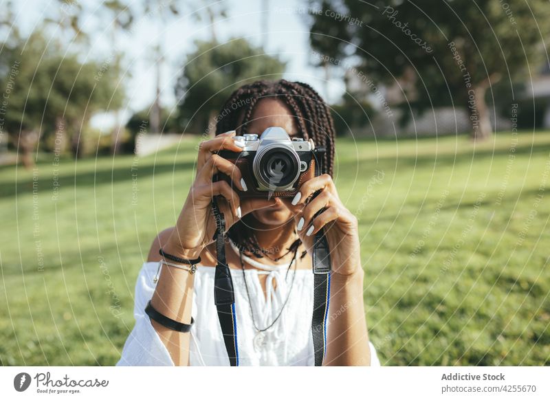 Anonyme schwarze Frau, die mit der Kamera fotografiert Fotograf Fotoapparat fotografieren einfangen Gedächtnis Moment Rasen Park Fotografie Hobby Afroamerikaner