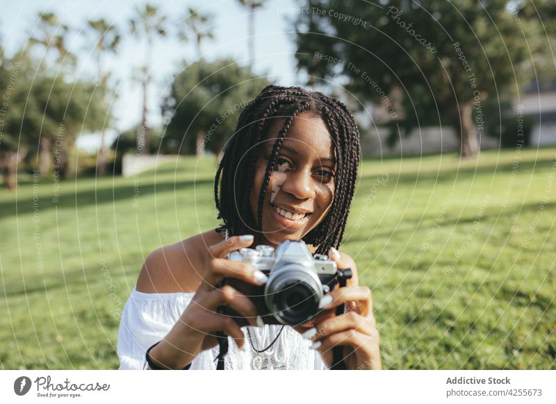 Schwarze Frau fotografiert mit Kamera Fotograf Fotoapparat fotografieren einfangen Gedächtnis Moment Rasen Park Fotografie Hobby Afroamerikaner schwarz Sommer
