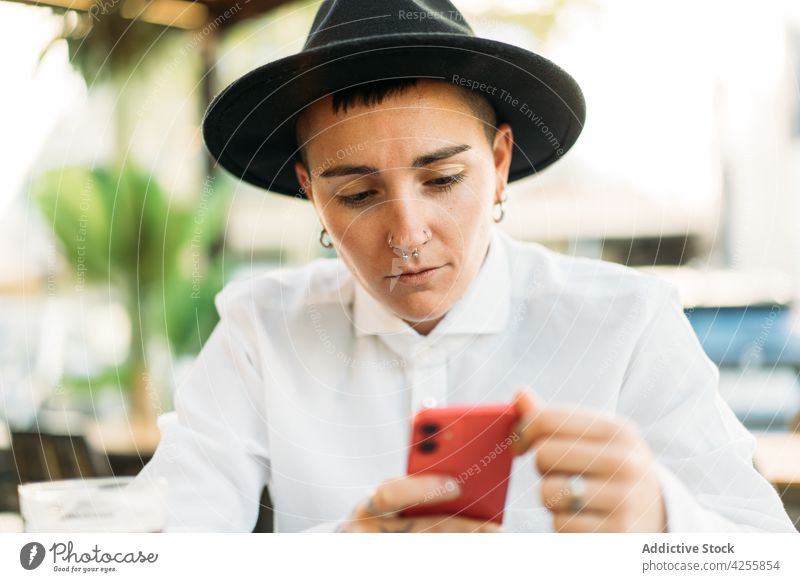 Nachdenklicher Junge mit Smartphone im Cafe Frau Transgender Geschlecht Telefon exzentrisch Identität queer Stil agender ernst Gerät Denken Wildfang weißes Hemd