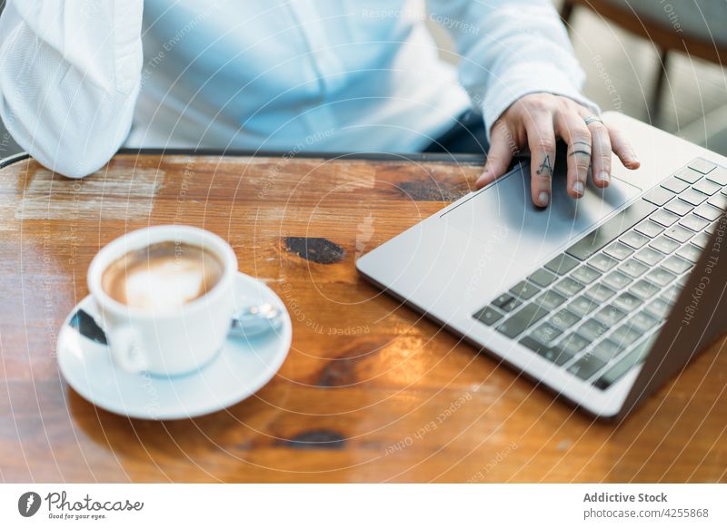 Person, die am Laptop tippt, sitzt am Tisch mit Kaffee Telearbeiter benutzend Arbeit freiberuflich Internet Tippen Latte Tasse Surfen beschäftigt online Gerät