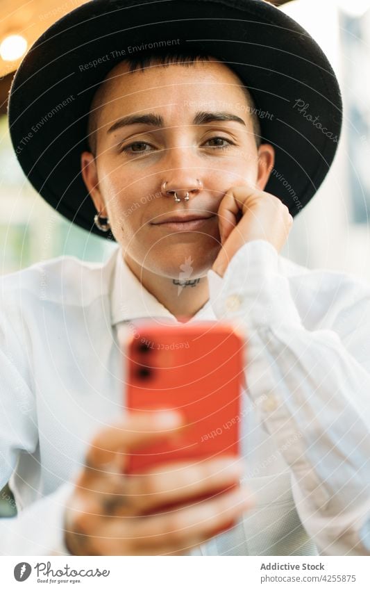 Nachdenklicher Junge mit Smartphone im Cafe Frau Wildfang Identität queer merkwürdig alternativ Denken Stil exzentrisch Transgender Apparatur neutral Telefon