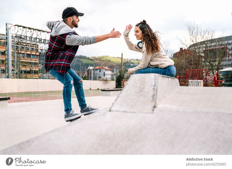 Mann gibt einer Frau fünf, während er auf Freeline-Skates übt heiter Freund Lächeln üben freeline Schlittschuh driften Zusammensein Aktivität Energie Stunt
