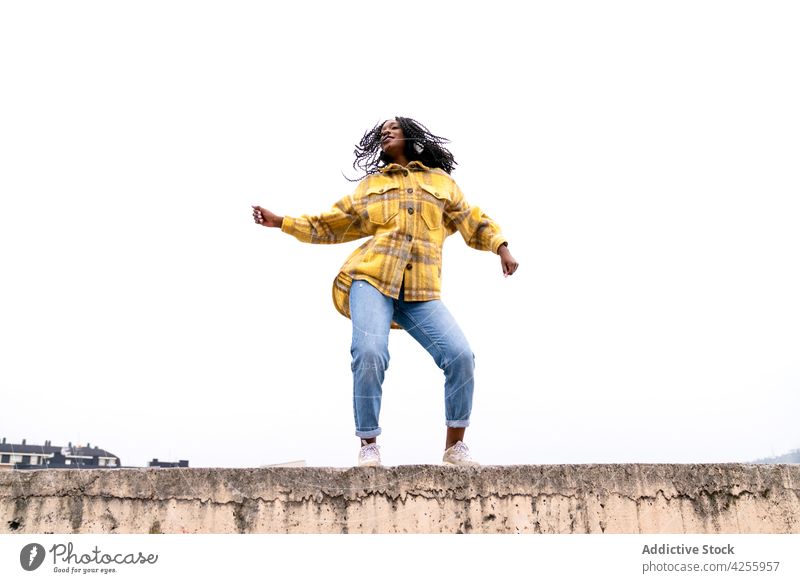 Energetische schwarze Frau tanzt auf Betongrenze sorgenfrei schütteln Tanzen sich[Akk] bewegen Freizeit Freestyle dynamisch Bewegung genießen Aktion