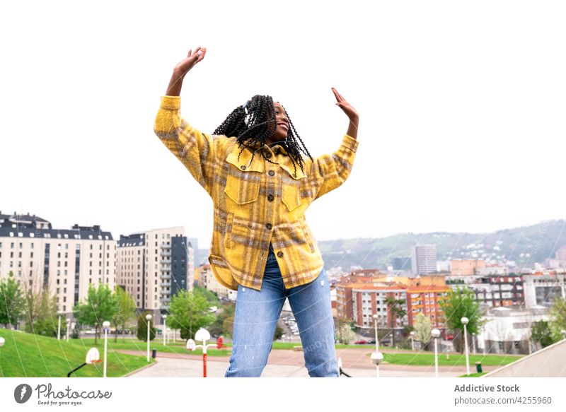 Energetische schwarze Frau tanzt mit der Stadt im Hintergrund Kopfhörer hören sorgenfrei schütteln Tanzen sich[Akk] bewegen Freizeit Musik Freestyle dynamisch
