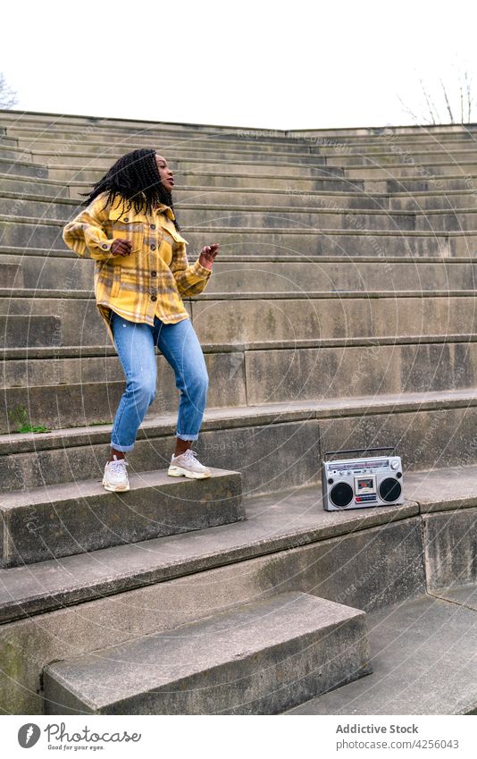 Schwarze Frau hört Musik und tanzt zuhören genießen Gesang Boombox unterhalten cool positiv Blaster tragbar retro altmodisch heiter lässig jung tausendjährig