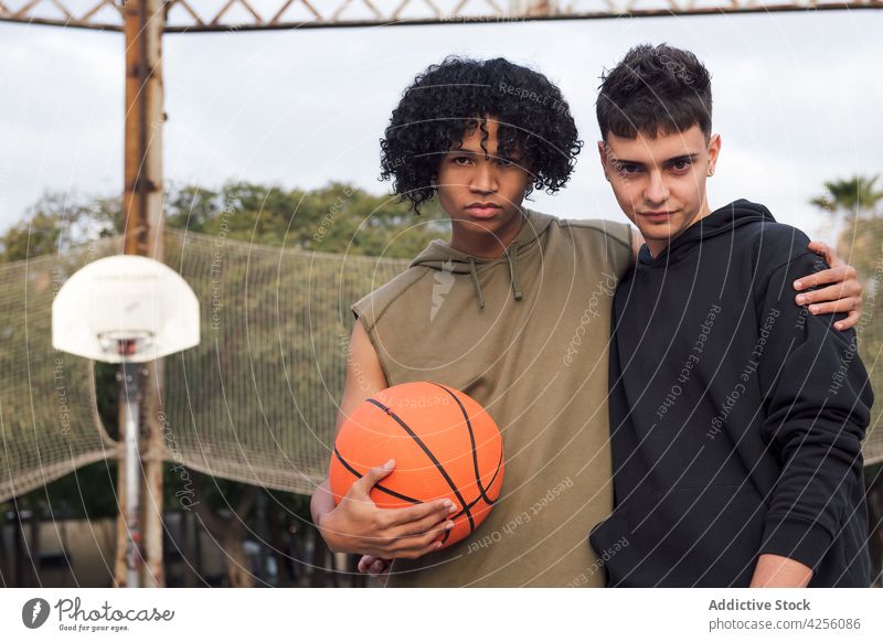 Multirassische Freunde stehen in der Nähe des Netzes mit Basketball Männer Spieler Sport Sportpark Freizeit Hobby männlich Teenager Park Freundschaft jung
