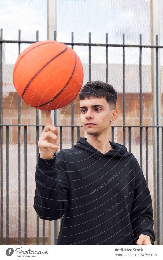 Männlicher Teenager, der einen Basketball auf dem Finger dreht Mann spinnen Fähigkeit üben Hobby Spiel Sport Aktivität ernst männlich Training Spieler Straße