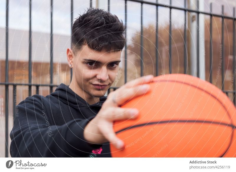 Männlicher Teenager hält Basketball auf dem Boden Mann Beteiligung Fähigkeit üben Hobby Spiel Sport Aktivität männlich Training Spieler Straße Freizeit jung