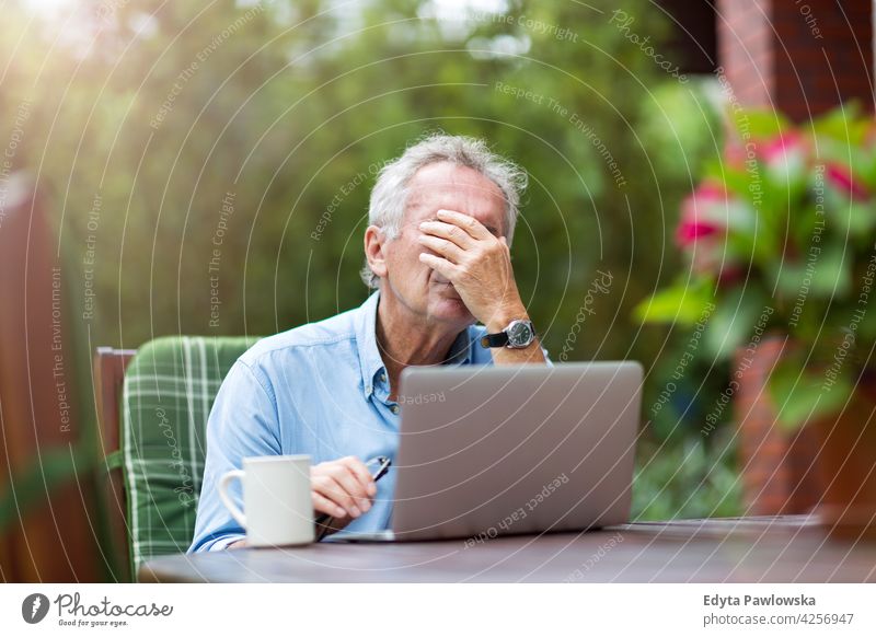 Senior Mann schaut gestresst bei der Arbeit am Laptop Computer Technik & Technologie arbeiten Internet benutzend Notebook alt Männer männlich heimwärts Haus