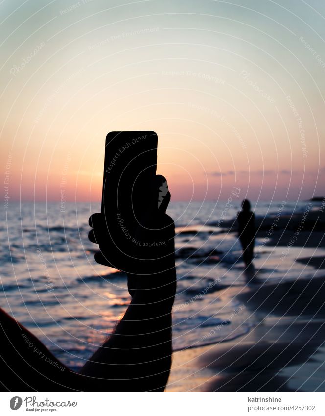 Mann nimmt ein Sonnenuntergangsfoto von Freundin mit dem Handy auf Himmel MEER Männer fotografierend Mädchen Frauen Silhouette gesichtslos Funktelefon Natur