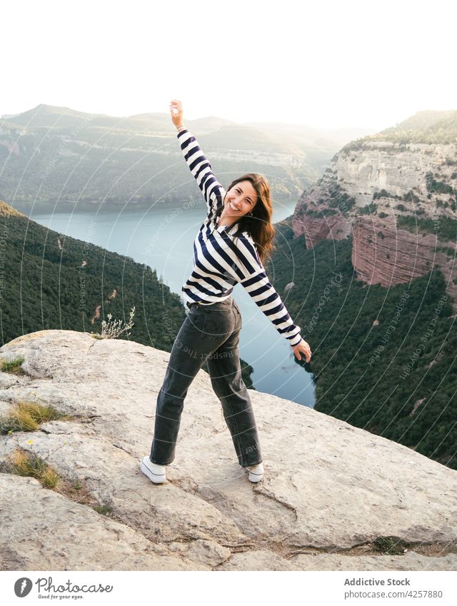 Zufriedene junge hispanische Frau, die auf einem felsigen Berg in einer Schlucht steht Wanderung Klippe Reisender Natur Glück erkunden Ausflug Fluss Feiertag