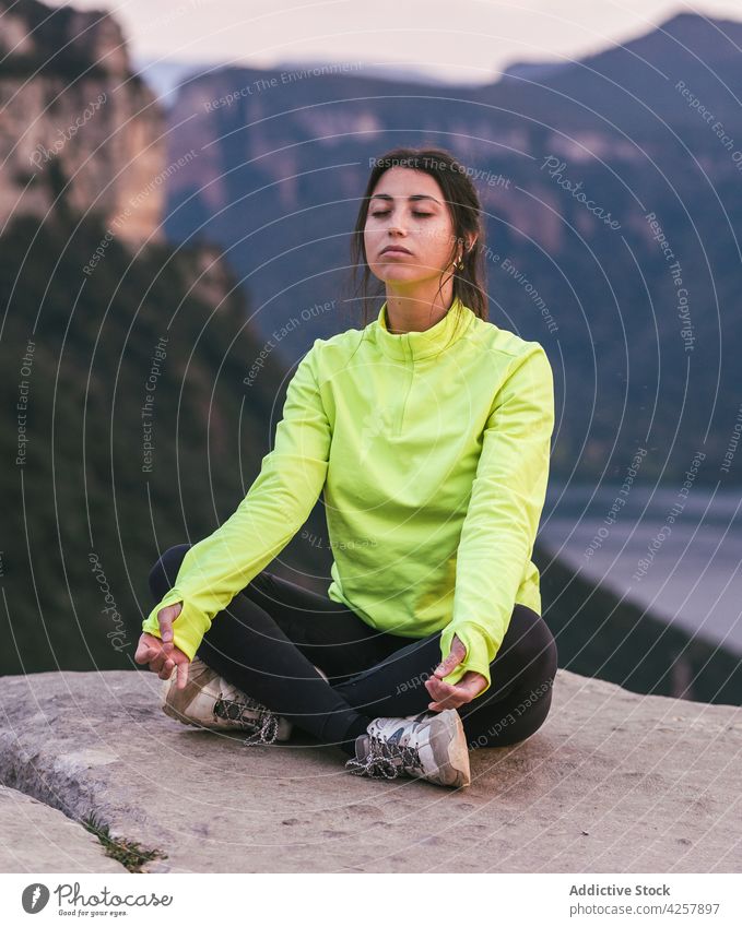 Junge hispanische Frau meditiert in Lotus-Pose auf Klippe Rand in felsigen Schlucht padmasana meditieren Augen geschlossen Yoga Achtsamkeit Natur Harmonie