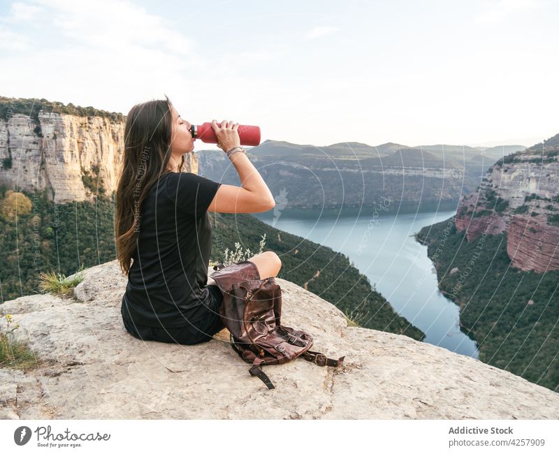 Junge Frau trinkt Wasser, während sie sich auf einer felsigen Klippe beim Wandern erholt trinken Berge u. Gebirge Wanderer Trekking müde Erholung Fluss reisen