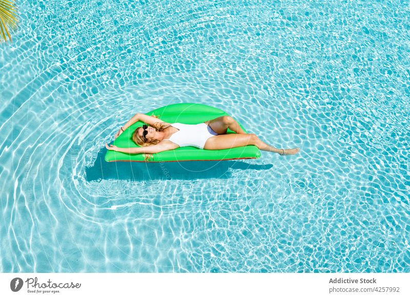 Attraktive fröhliche Frau schwimmt auf Luftmatratze im Pool Kälte Badebekleidung Sonnenbad Bräune Paradies sich[Akk] entspannen Resort aufblasbar schwimmen