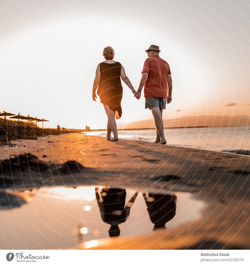Anonymes Paar spaziert am Sandstrand bei Sonnenuntergang Händchenhalten schlendern Strand Meeresküste romantisch Meeresufer amour Zusammensein Urlaub Küste