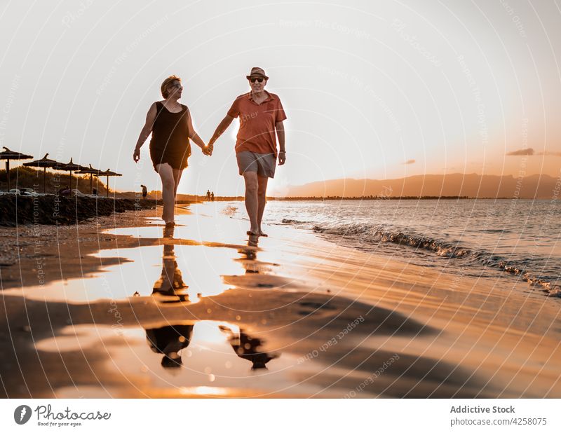 Ehepaar spaziert am Sandstrand bei Sonnenuntergang Paar Händchenhalten schlendern Strand Meeresküste romantisch Meeresufer amour Zusammensein Urlaub Küste