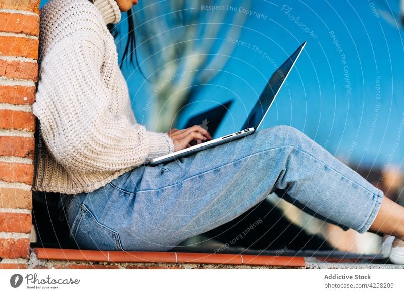 Trendige junge ethnische Frau arbeitet an einem Laptop auf der Straße Arbeit abgelegen trendy Internet freiberuflich benutzend Netbook asiatisch dunkles Haar