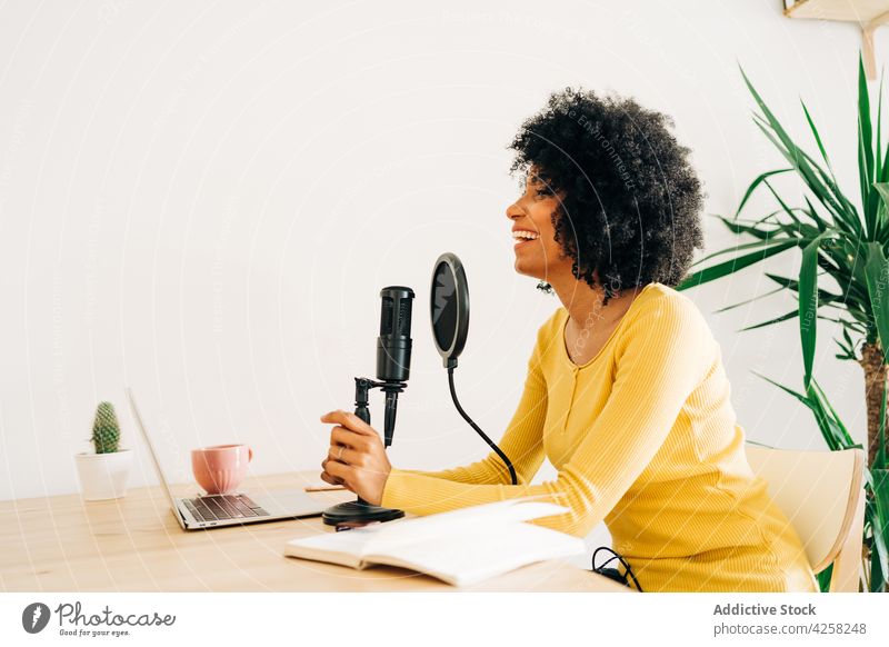 Positive junge afroamerikanische Frau im Gespräch bei einem Online-Radiosender Podcast reden Mikrofon Laptop Lächeln Arbeit positiv Aufzeichnen Kommunizieren