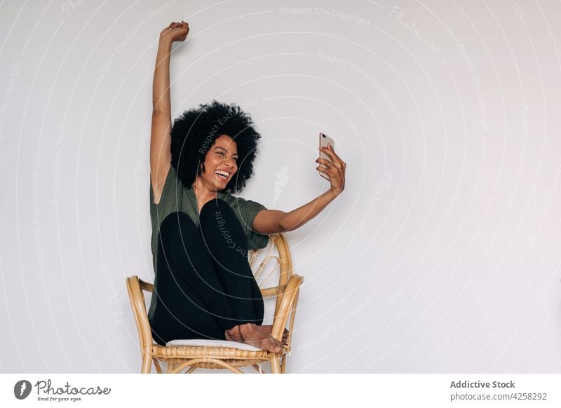 Positive schwarze Frau macht Selfie in der Nähe von grünen Topfpflanzen positiv Lächeln Glück Pflanze eingetopft Smartphone fotografieren heiter benutzend