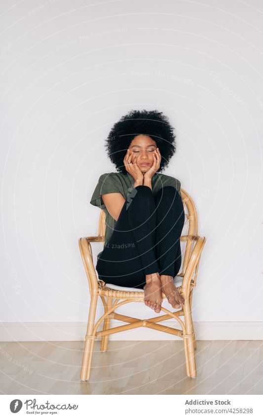 Schwarze Frau stützt das Kinn auf die Hände auf einem Holzstuhl Vorschein positiv selbstbewusst Zeitgenosse charismatisch Freude Barfuß schwarz Glück