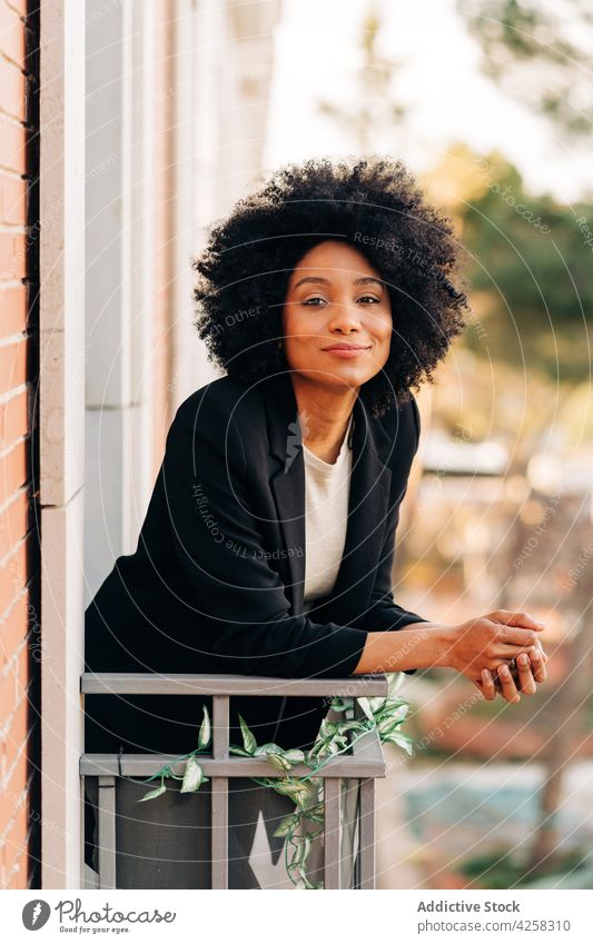 Entspannte schwarze Frau auf Balkon sich[Akk] entspannen Lächeln Glück Straße genießen Afroamerikaner verträumt ethnisch Großstadt modern Afro-Look Frisur