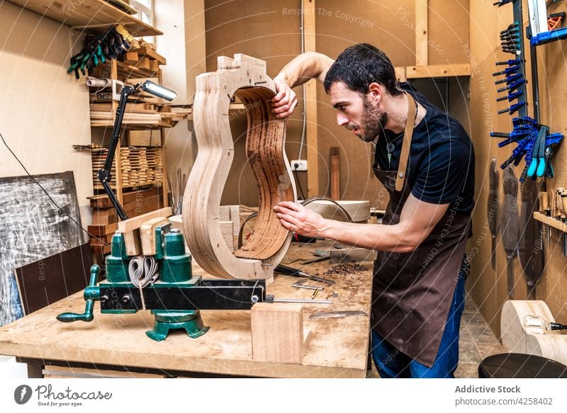 Geigenbauer baut Gitarre am Tisch in der Werkstatt Zupfinstrumentenmacher bauen Genauigkeit präzise Beruf Fähigkeit Mann Kleinunternehmen machen Musical