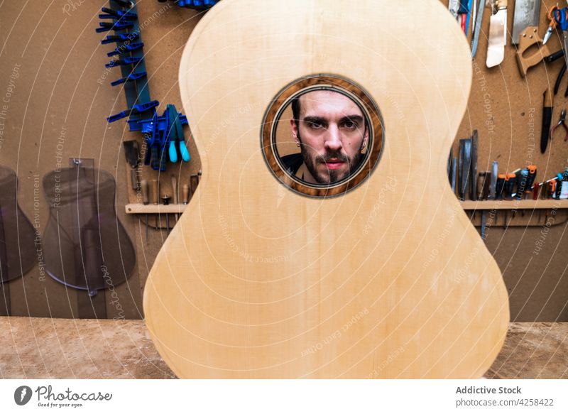 Crop-Handwerker hinter dem Resonanzboden der Gitarre im Arbeitsraum Kunstgewerbler Instrument Musical Klassik Golfloch Mann Kleinunternehmen Werkstatt