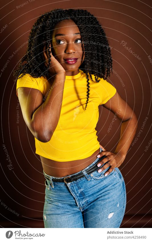 Schwarze Frau stehend mit Händen im Haar charmant feminin tausendjährig Stil Körperhaltung Vorschein Kurve cool Afro-Look Frisur krause Haare selbstbewusst