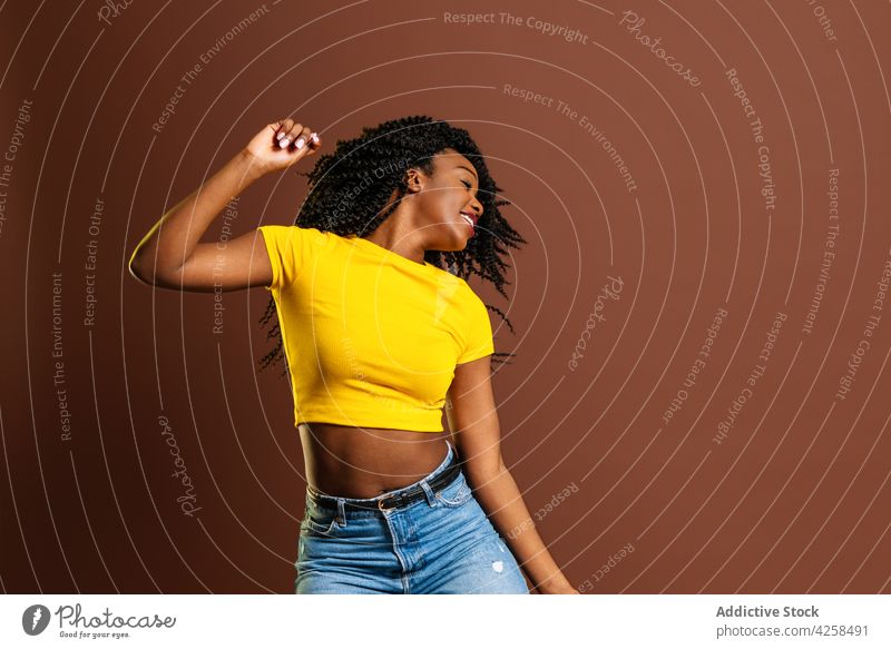 Lächelnde schwarze Frau, die beim Tanzen die Hände hebt positiv sich[Akk] bewegen Rhythmus Aktion Bewegung Freizeit genießen Augen geschlossen cool heiter