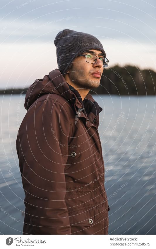 Junger Mann in Oberbekleidung steht in der Nähe des plätschernden Flusses verträumt Küste friedlich Natur Umwelt Freiheit Harmonie stumm männlich lässig See